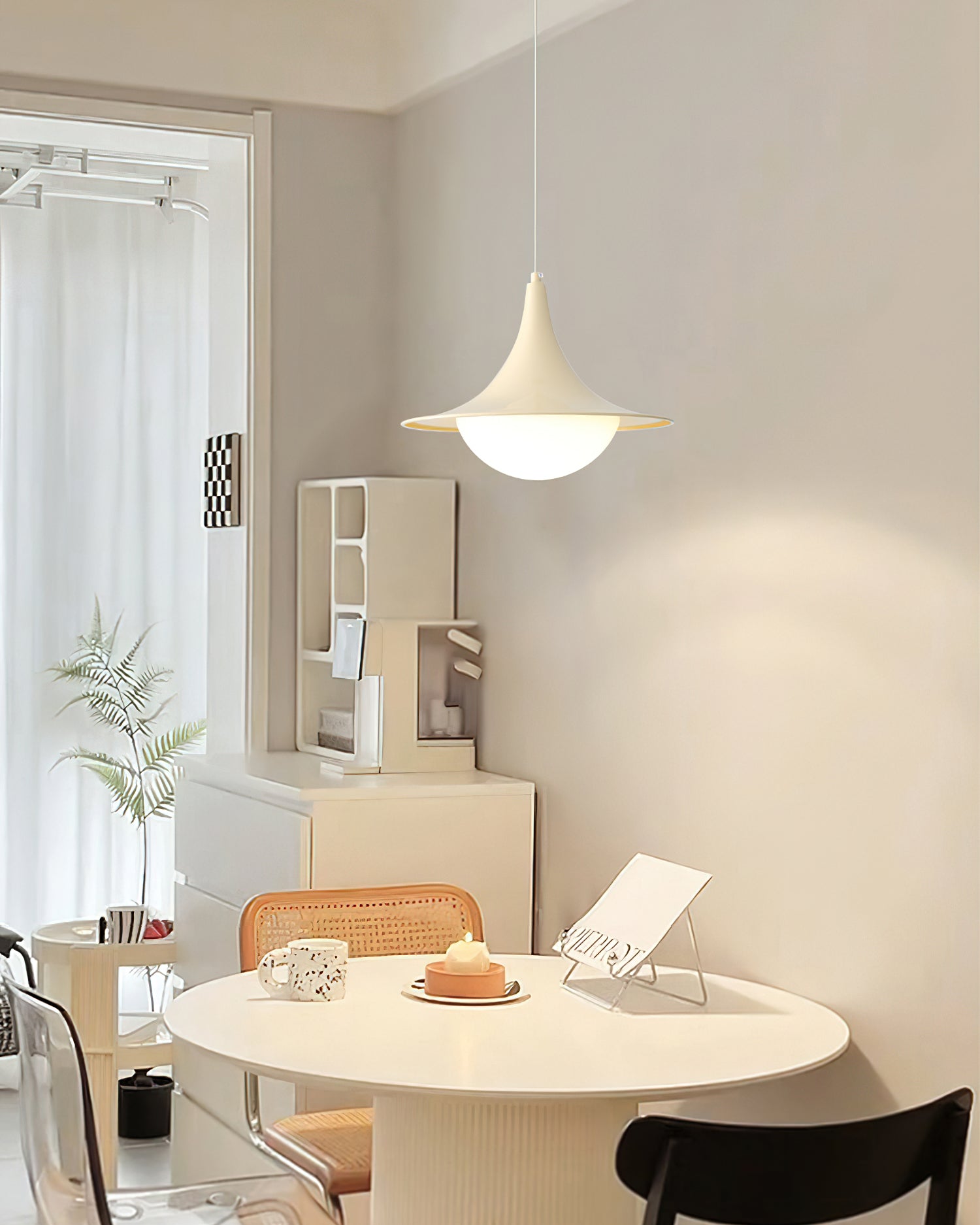 Modern dining area with round table, chairs, and pendant light.