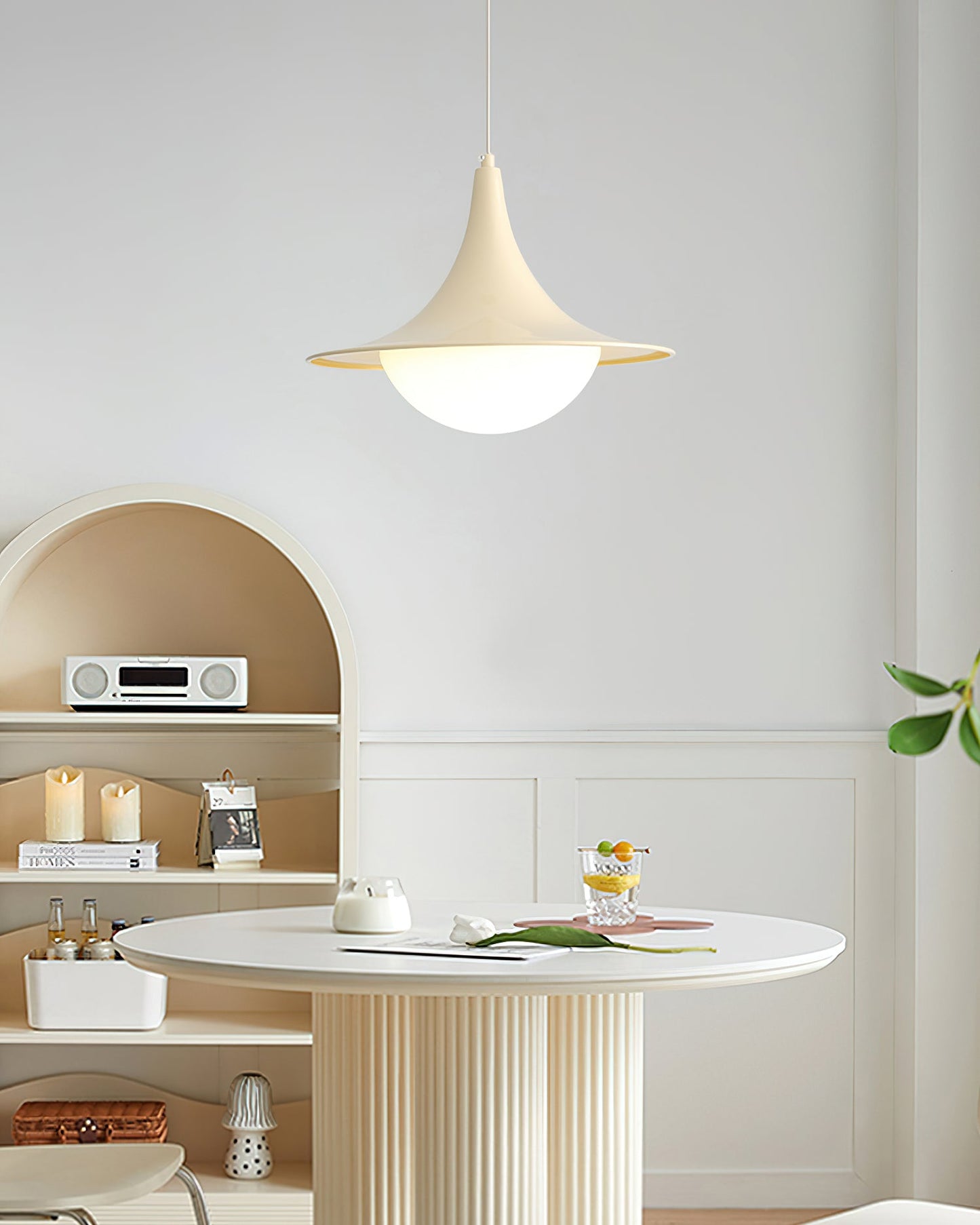 Modern interior with a round white table, pendant light, and shelves.
