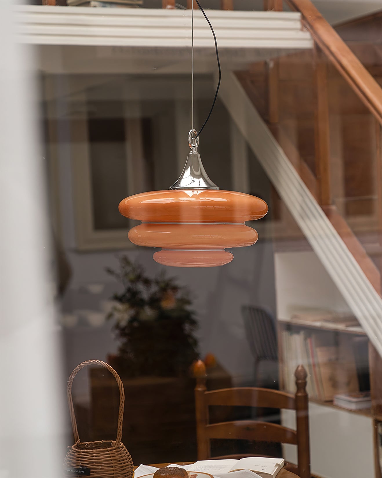 Orange pendant light hanging in a room with furniture and decor.