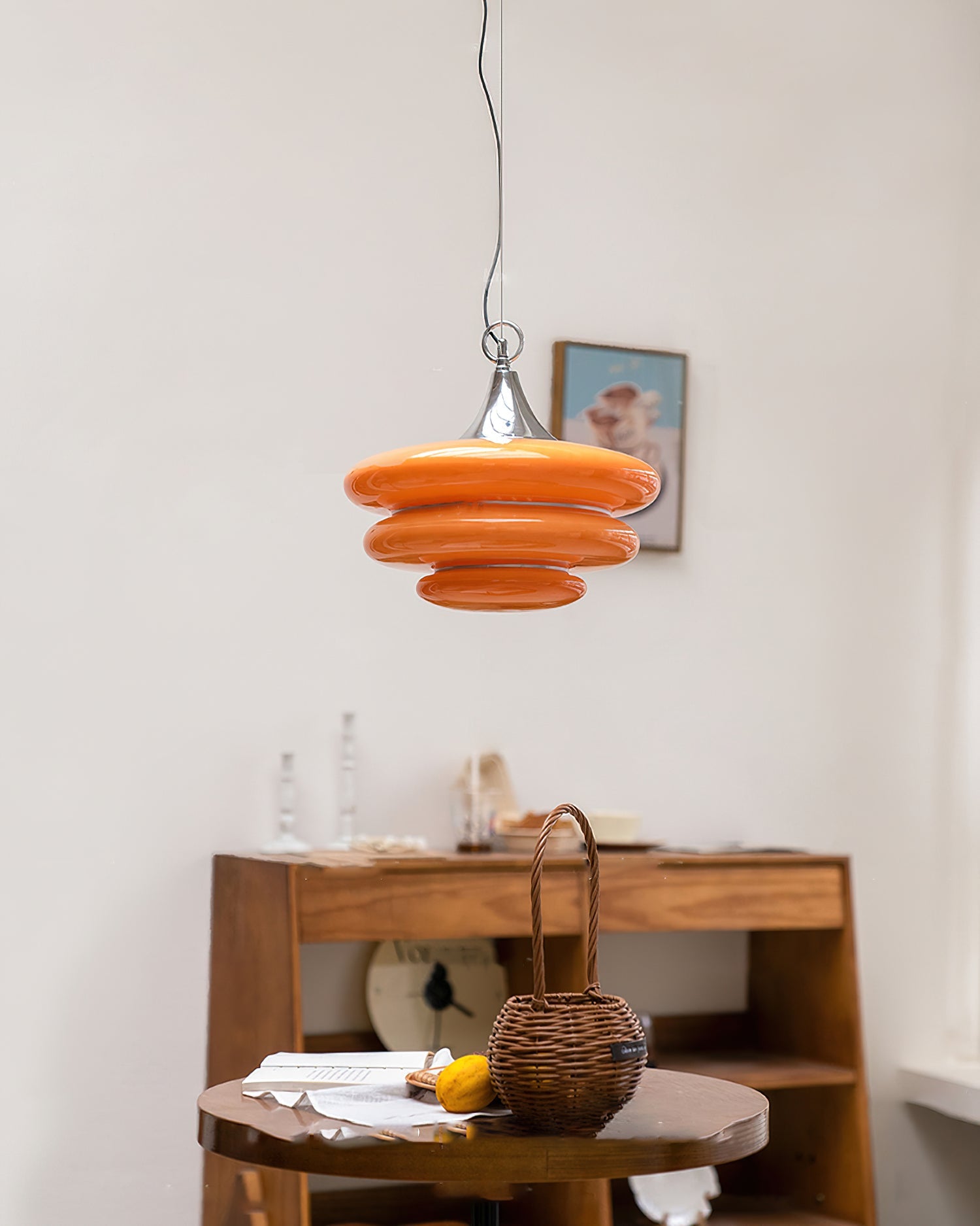 Orange pendant light hanging above a wooden table with a blurred background
