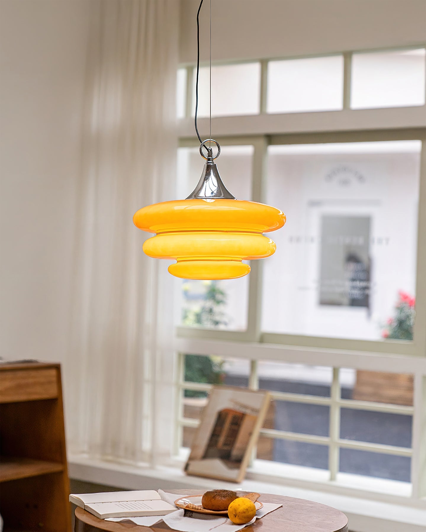 Yellow pendant light hanging in a room with a window in the background