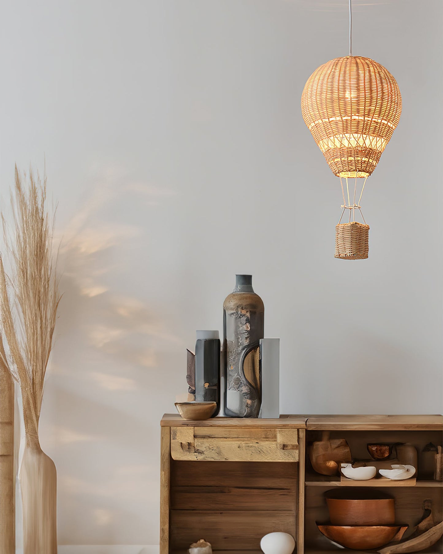 Woven pendant light hanging above a wooden shelf with decorative items.