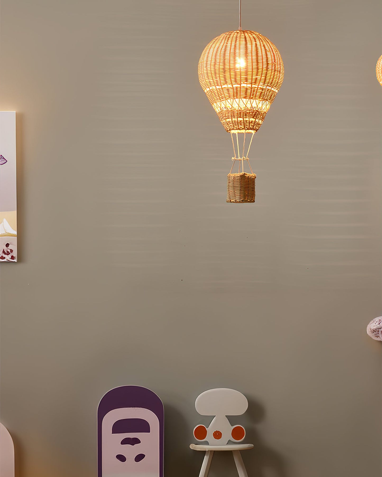 Woven lamp shaped like a hot air balloon hanging on a wall with children's furniture below.