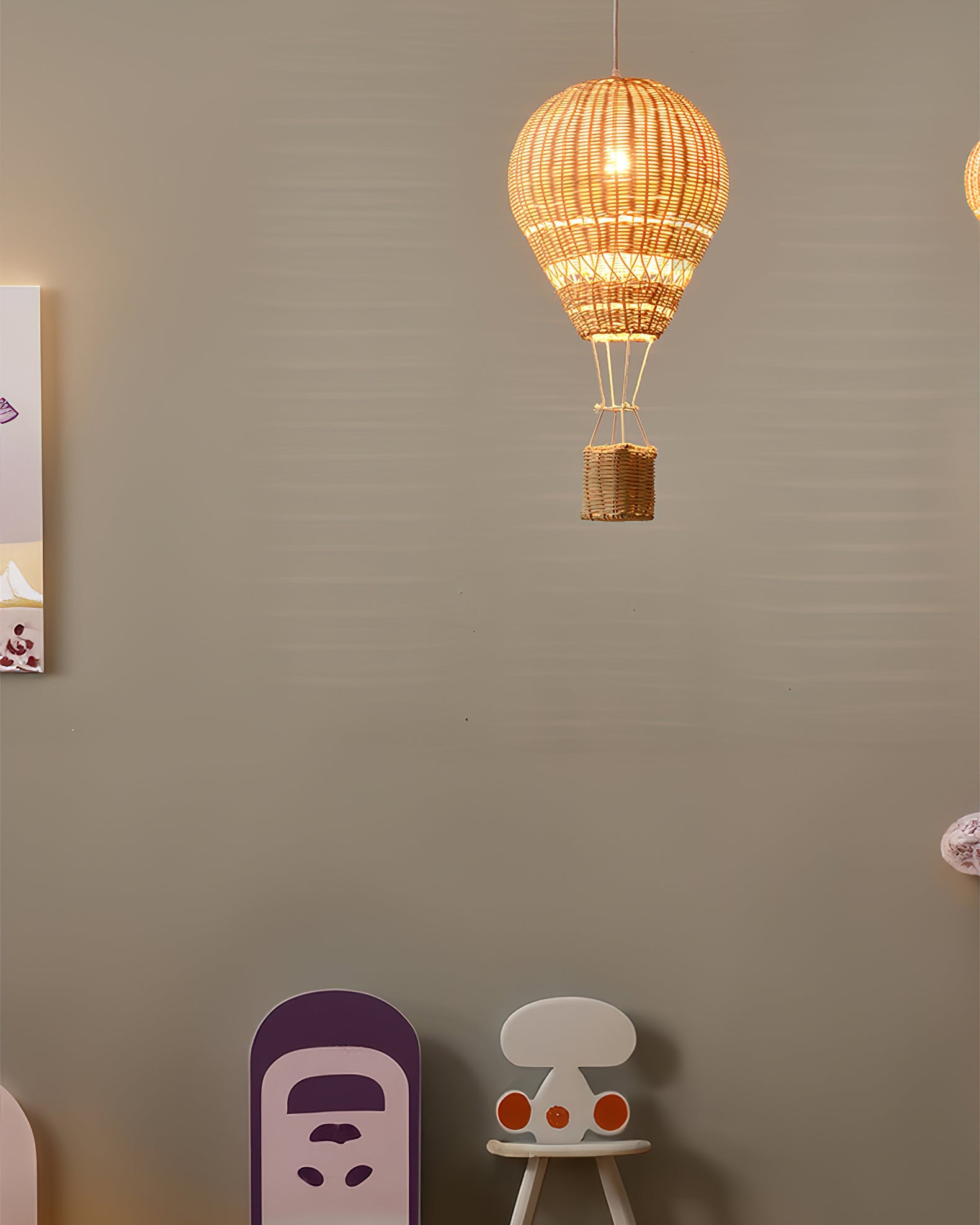Woven lamp shaped like a hot air balloon hanging on a wall with children's furniture below.